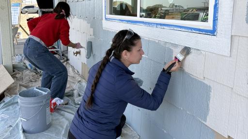 Student painting exterior of house